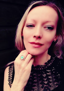 model wearing a celtic sterling silver mood ring with a blue green color meaning