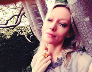 blonde model wearing a circular mood ring by a tree