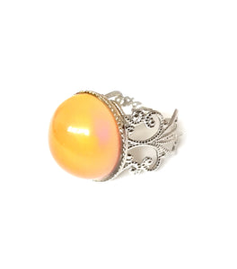 a circular mood ring turning an orange color with a silver brass band