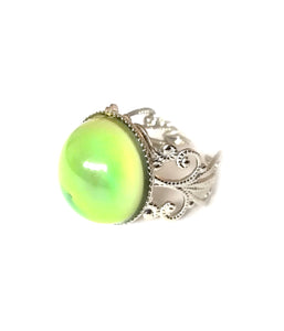 a mood ring showing a green yellow mood with a silver brass band
