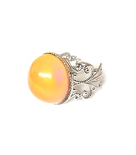 Load image into Gallery viewer, a circular mood ring turning an orange color with a silver brass band