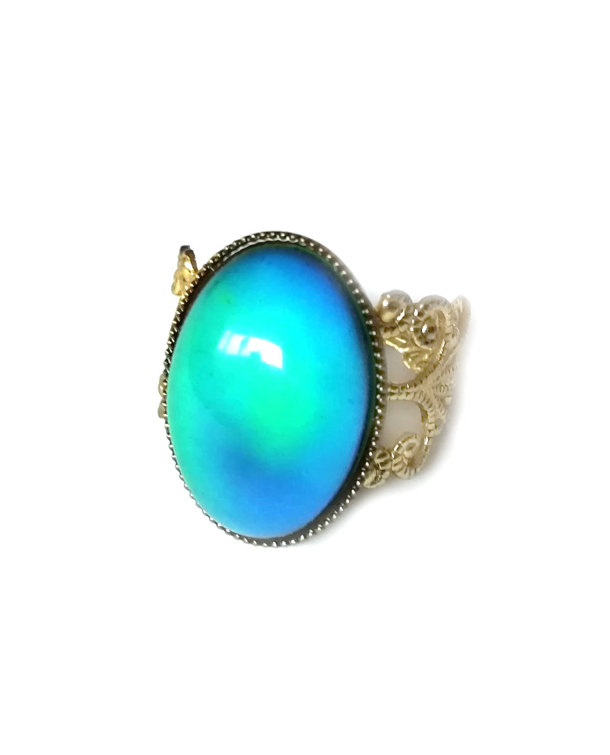 an oval mood ring with a green blue mood color set on a gold brass band