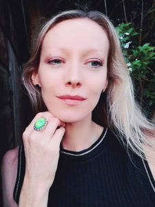 blonde model wearing a large mood ring with a green color mood